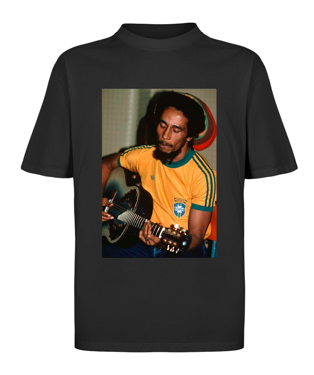 Camiseta oversized com estampa icônica de Bob Marley vestindo a camisa da seleção brasileira, simbolizando a conexão entre reggae e futebol.
